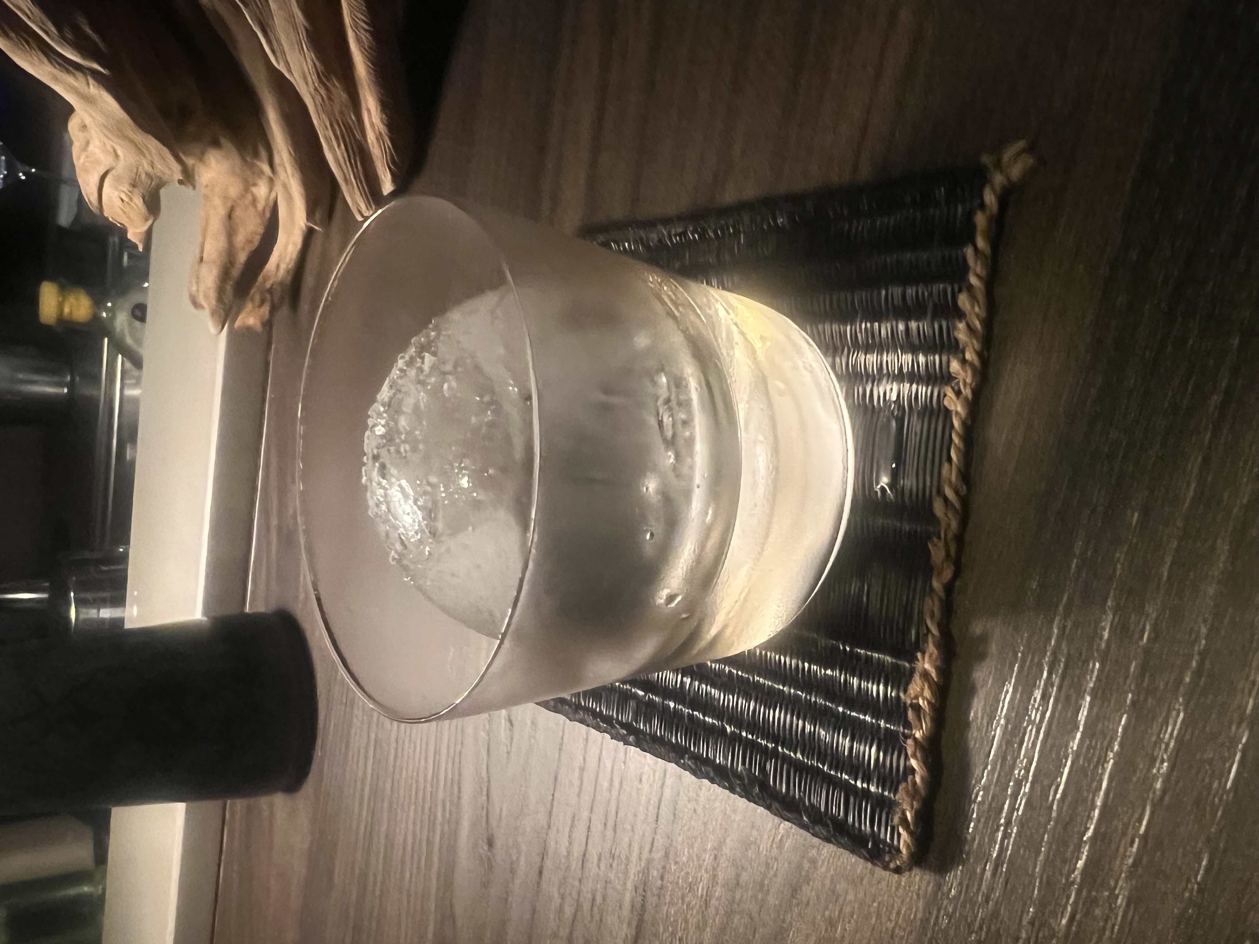 那晚的其中一杯,擺在編織墊上、聚光燈打下來。