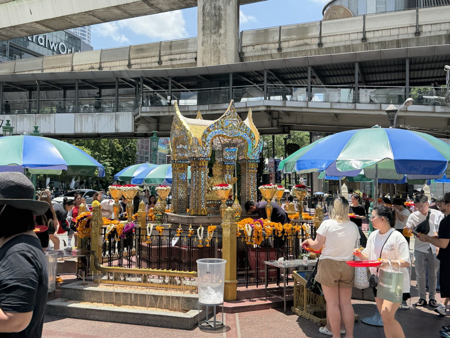 四面佛就在 CentralWorld 對面，藍綠陽傘下都是捧著供品來拜的人。